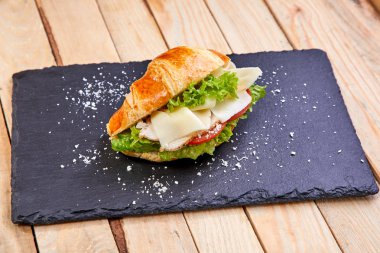 Karanlık tahtada jambonlu kruvasan, yakın plan.  