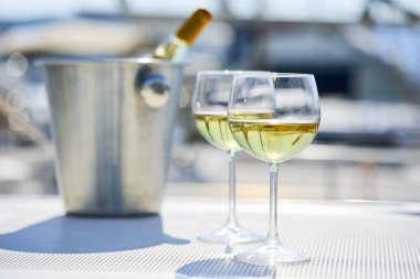 Çift kadehlerin ve kova ile yatta beyaz şarap şişesi