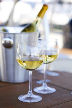 Çift kadehlerin ve kova ile yatta beyaz şarap şişesi