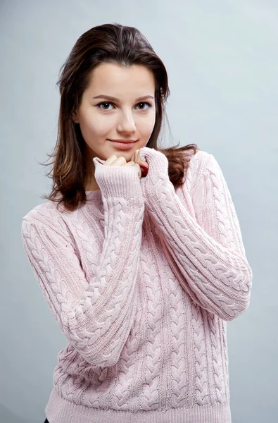 灰色の背景にポーズのセーターを着ての美しい若い女性の肖像画 — ストック写真