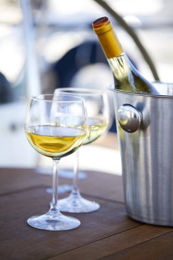 Çift kadehlerin ve kova ile yatta beyaz şarap şişesi
