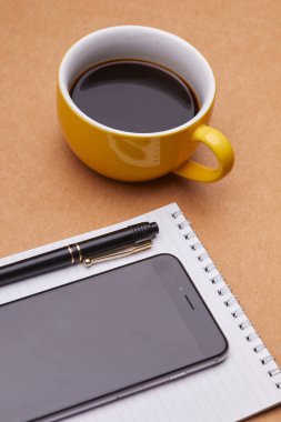 Ofis masaları, iş kavramı üzerinde not defteri ve kahve Kupası ile modern smartphone 