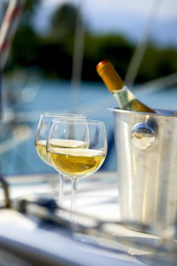 Çift kadehlerin ve kova ile yatta beyaz şarap şişesi