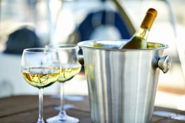 Çift kadehlerin ve kova ile yatta beyaz şarap şişesi