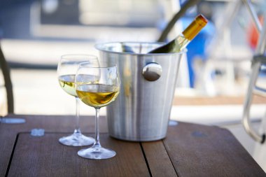 Çift kadehlerin ve kova ile yatta beyaz şarap şişesi