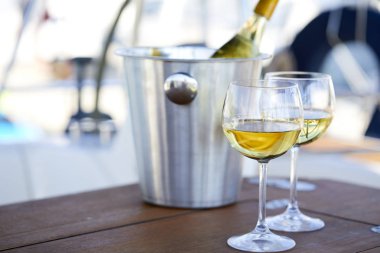 Çift kadehlerin ve kova ile yatta beyaz şarap şişesi