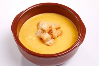beyaz zemin üzerinde bir kapta croutons kabak kremalı çorba