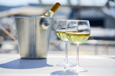 Çift kadehlerin ve kova ile yatta şarap şişesi