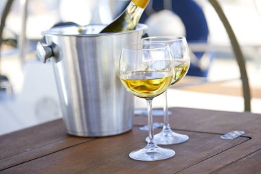 Çift kadehlerin ve kova ile yatta şarap şişesi