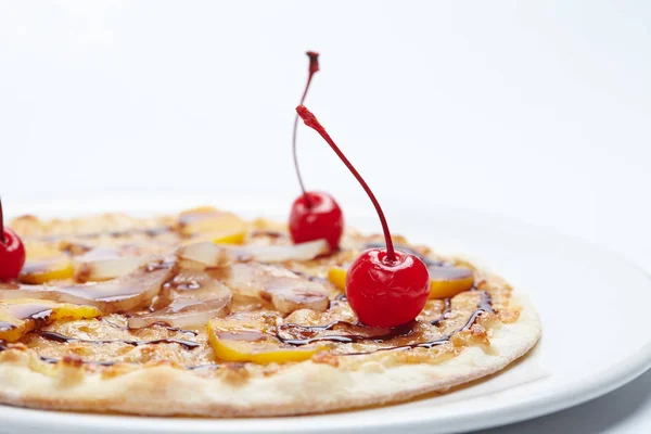 sweet pizza with cherries on white plate, close-up