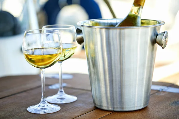 Pair of wineglasses and bucket with wine bottle on yacht