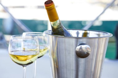 Çift kadehlerin ve kova ile yatta beyaz şarap şişesi