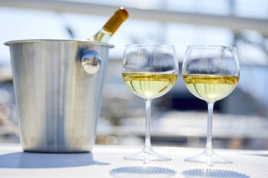 Çift kadehlerin ve kova ile yatta beyaz şarap şişesi