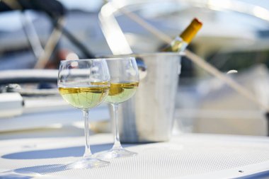 Çift kadehlerin ve kova ile yatta beyaz şarap şişesi