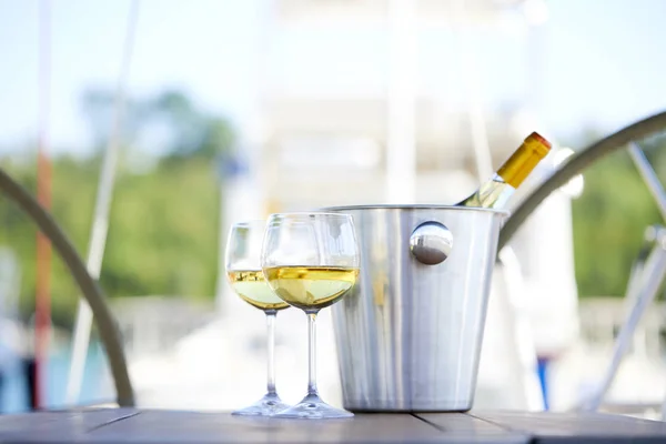 Pair of wineglasses and bucket with white wine bottle on yacht