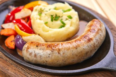 ahşap arka plan üzerinde tavada patates püresi ve sebze ile sosis