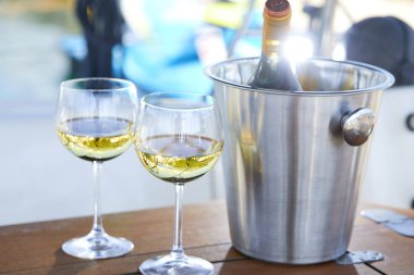 Çift kadehlerin ve kova ile yatta beyaz şarap şişesi