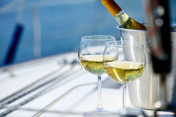 Pair of wineglasses and bucket with white wine bottle on yacht