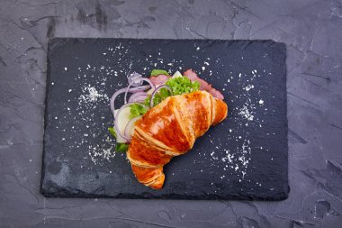 Karanlık tahtada jambonlu kruvasan, yakın plan.  