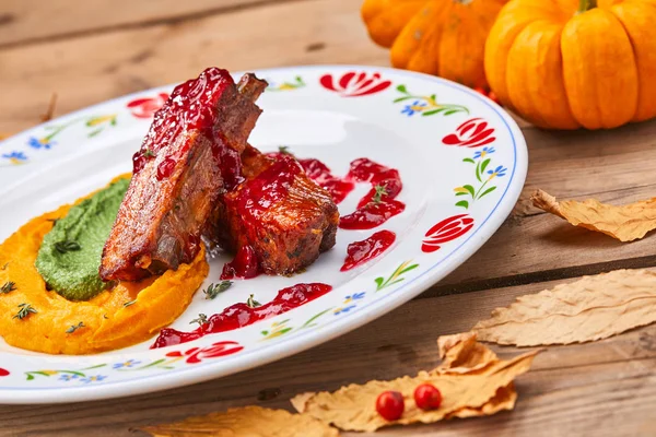 grilled ribs with pumpkin puree on white plate, close-up
