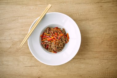 Beyaz plaka üzerinde sığır eti ve Chopsticks ile kızartma erişte soba, yakın çekim 