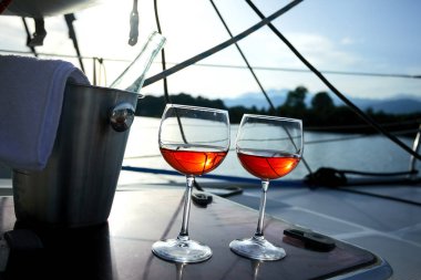 Çift kadehlerin ve kova ile yatta beyaz şarap şişesi