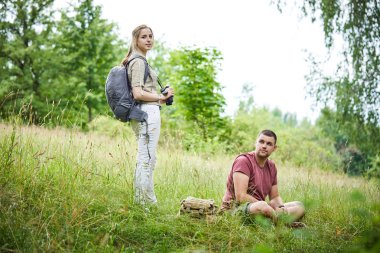 güneşli bir günde ormanda yürüyen dürbün ve sırt çantaları ile iki gezginler 