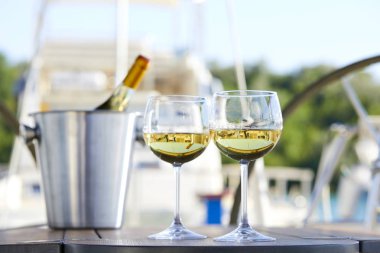 Çift kadehlerin ve kova ile yatta beyaz şarap şişesi