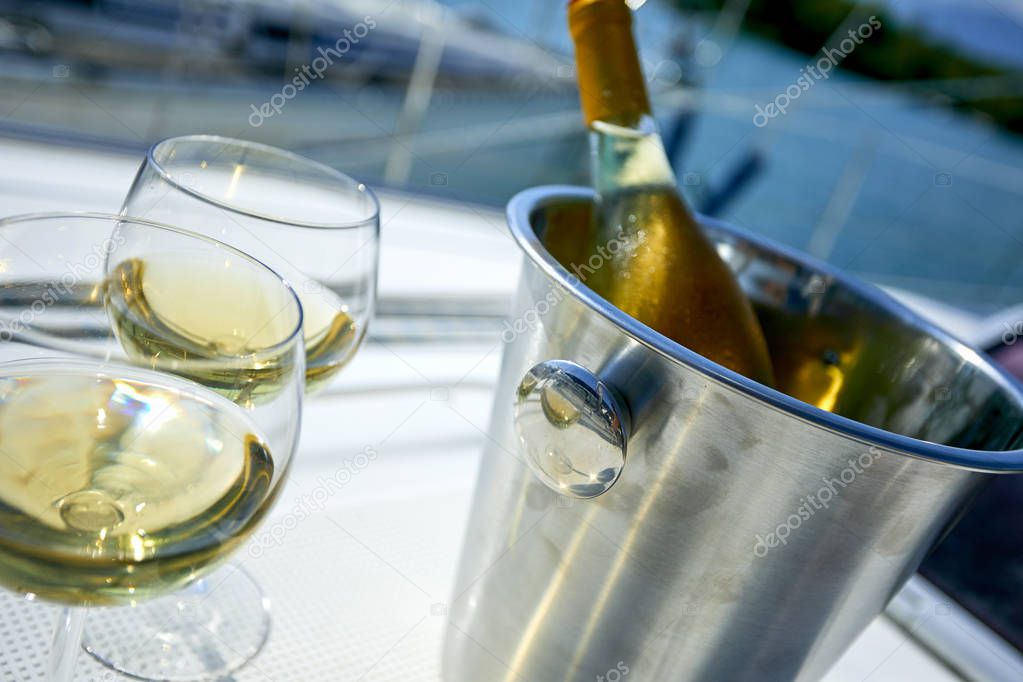 Pair of wineglasses and bucket with white wine bottle on yacht