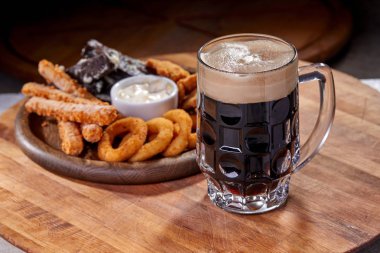 Ahşap kesme tahtasında meze ile servis edilen filtresiz bira pint, yakın çekim 