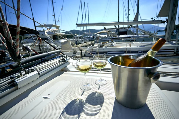 Pair of wineglasses with white wine and bucket with bottle on yacht