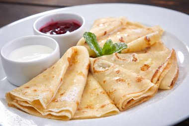 Krep ekşi krema ve beyaz tabakta berry sos ile yakın çekim 