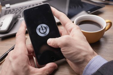 Erkek eller modern akıllı telefonu tutuyor. Ekranda güç düğmesi var. İş kavramı. 