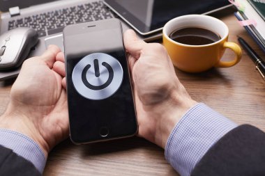 Erkek eller modern akıllı telefonu tutuyor. Ekranda güç düğmesi var. İş kavramı. 