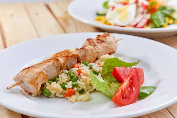 chicken kebab with rice and vegetables on white plate, close-up