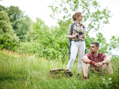 iki gezgin dürbün ve sırt çantası güneşli bir gün ormanda yakın çayır üzerinde dinlenme 