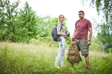 iki gezginler dürbün ve sırt çantası ile güneşli bir gün ormanda yakın çayır üzerinde dinlenme 