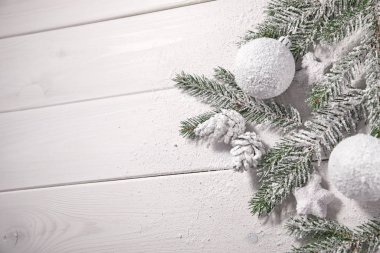 Masa arkasında süslemeleri olan karlı Noel ağacı dalları