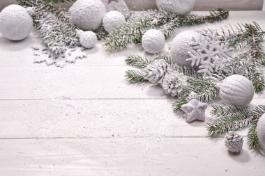 Masa arkasında süslemeleri olan karlı Noel ağacı dalları