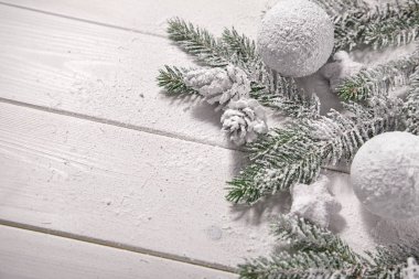 Masa arkasında süslemeleri olan karlı Noel ağacı dalları