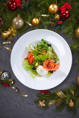 salad with salmon on plate with Christmas decoration on grey background