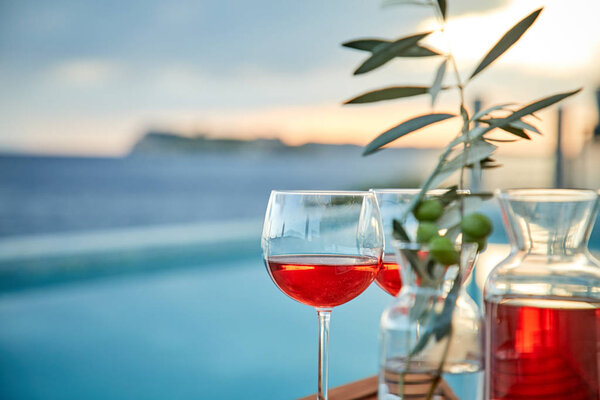 two glasses of rose wine with olives against blue water on pie