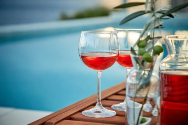 İskelede mavi suya karşı zeytinli iki bardak gül şarabı.