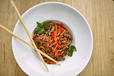 Kızarmış erişteli sobayı beyaz kasede sığır etiyle karıştır, yakın görüş. 