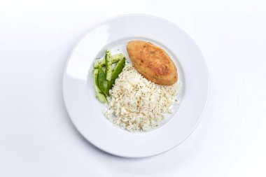 Pirinçli pirzola ve beyaz tabakta salatalık, yakın görüş. 