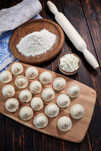 сырые пельмени с творогом на деревянной доске, вид снизу 