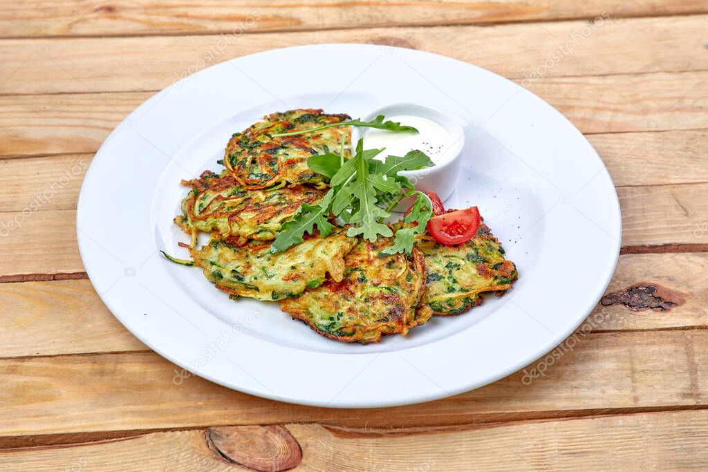 pancakes with zucchini and herbs on white plate, close view 