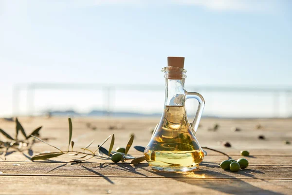 olive oil in bottle and branch of green olives, close view