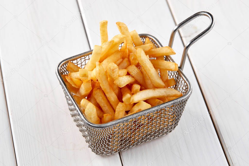 fried french fries in cooked basket, close view 