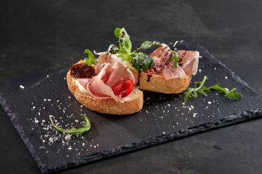 Koyu renkli taş tahtada etli ve sebzeli kanepeler, yakın görüş 